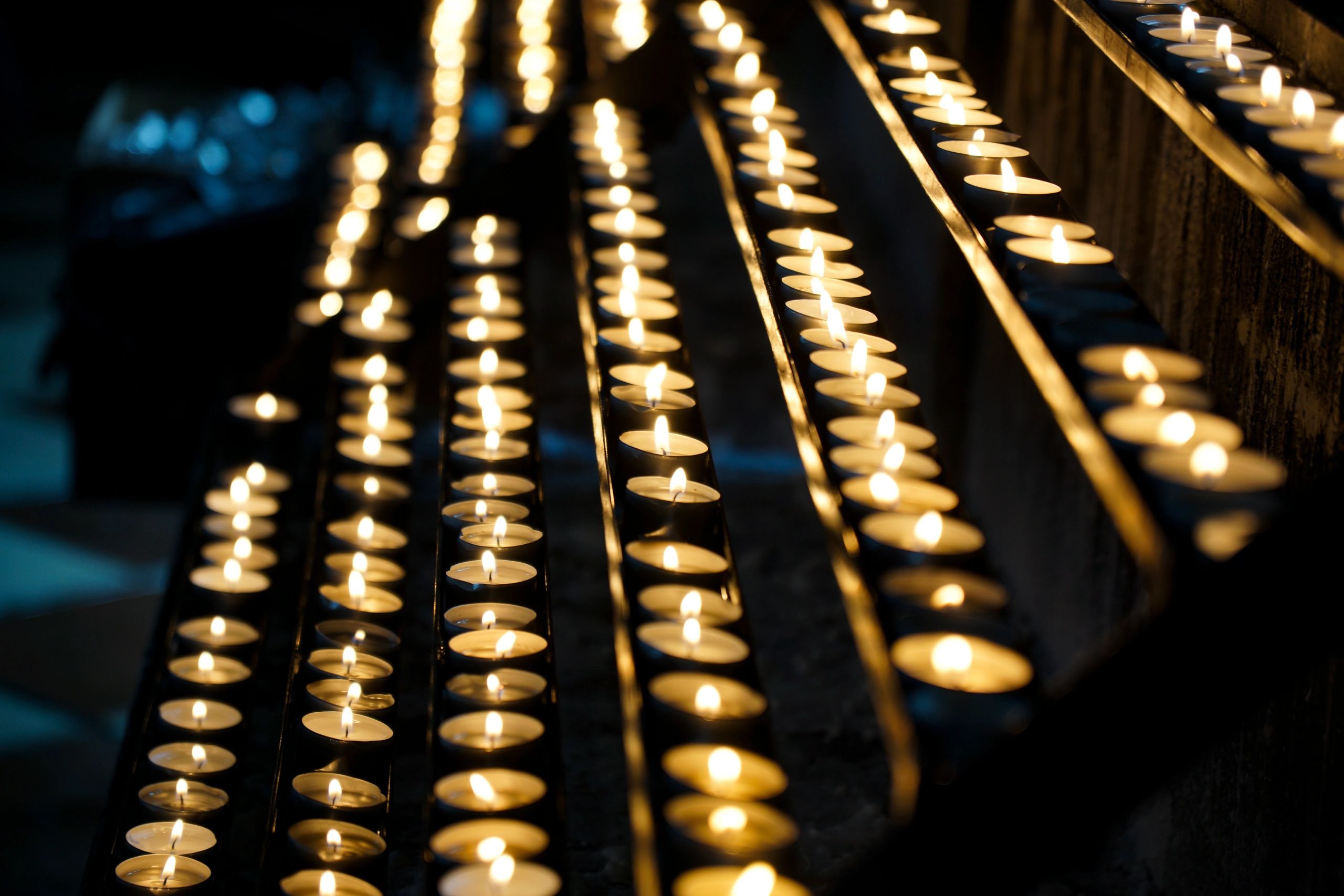 Rows of lit votive candles in a quiet place of reflection