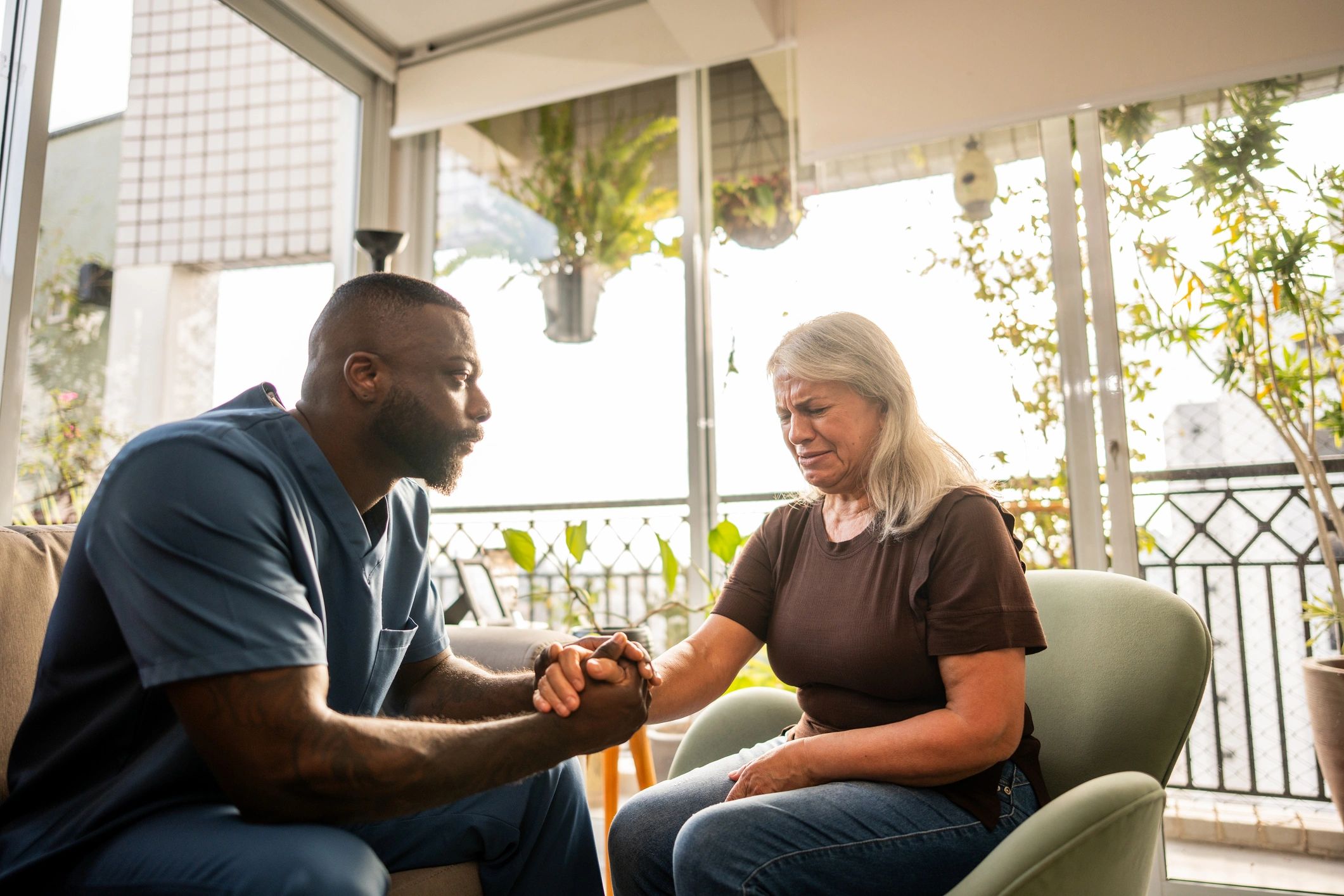 Caregiver comforting senior woman during house call