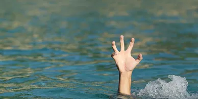 Hands and arms emerging from water making a V sign