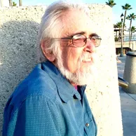 Portrait of Joe Rosenblatt outdoors wearing glasses and a blue shirt