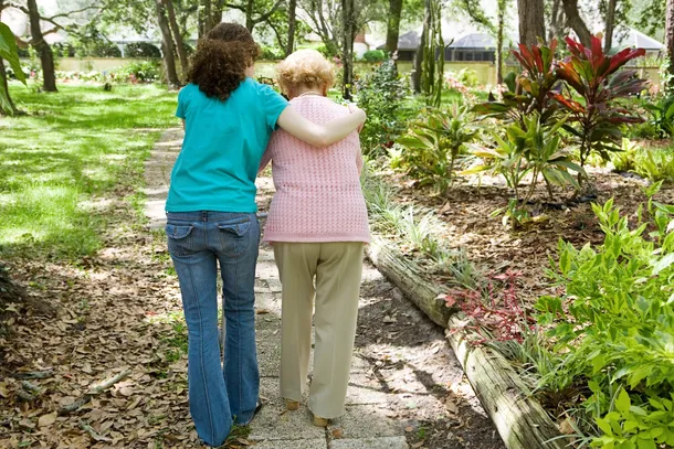 Two people walking together along a garden path, offering quiet support