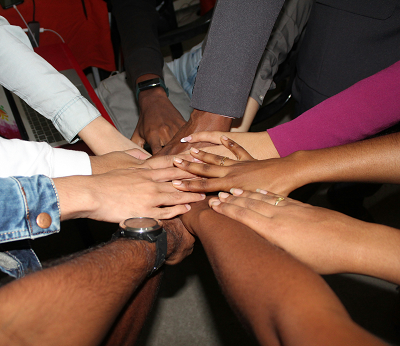 Multiple hands stacked together to represent support and community