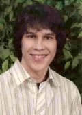 Portrait of a smiling person in front of green foliage